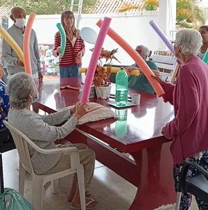 Idosos fazendo exercícios em grupo com espaguetes coloridos em uma instituição