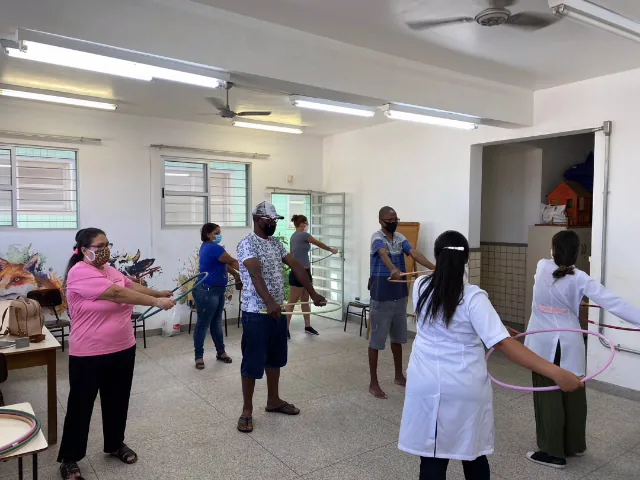 Grupo de idosos fazendo exercícios em sala com a fisioterapeuta
