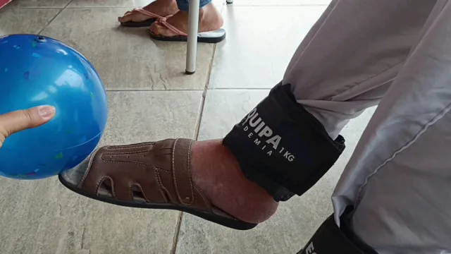 Pé com caneleira de peso empurrando uma bola azul