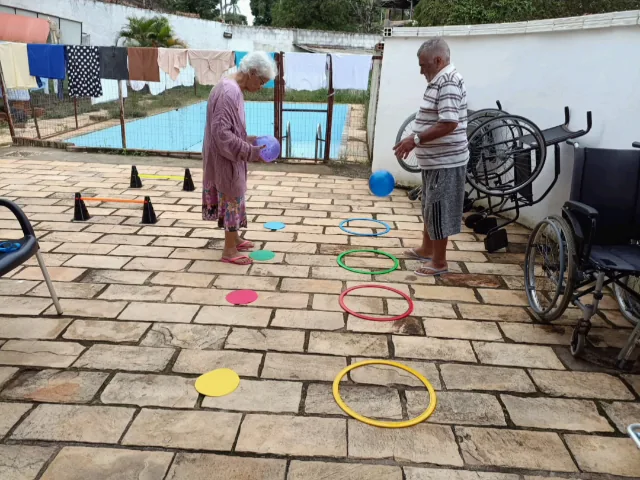 Idosos fazendo circuito ao ar livre com arcos, cones e bolas