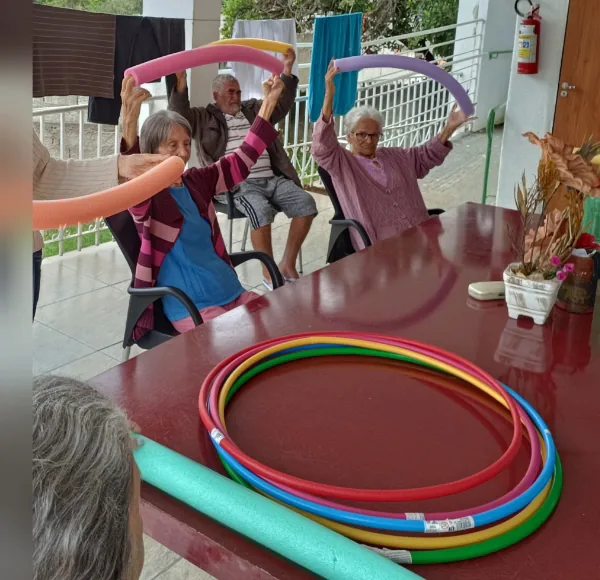 Idosas levantando espaguetes de piscina coloridos em atividade em grupo